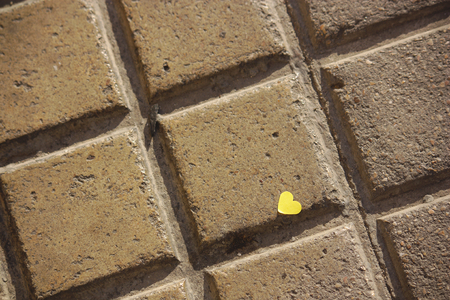A yellow heart on the brickwork floorの写真素材