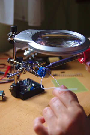 Workshop of a technician dedicated to electronic welding while working on the connection of a small...