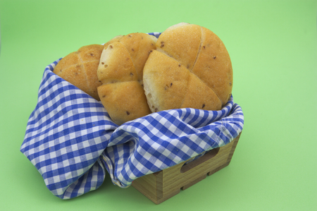 A few sweet breads inside a wooden crate and a rag of white and blue squares on a green background