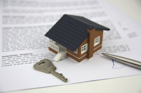 A house, a key to a door and the signature on the bank papers close the businessの写真素材