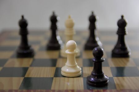 Concept of chase on the chess board. Two black and white pawns are stopped by 5 bishops on the board
