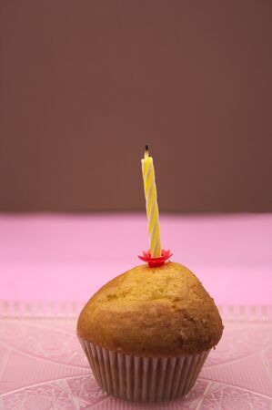 A cupcake with a candle off above with pastel colored backgroundsの写真素材
