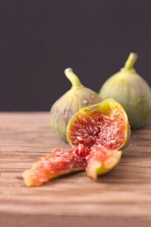 Image of some ripe figs on a wooden board with dark backgroundの写真素材