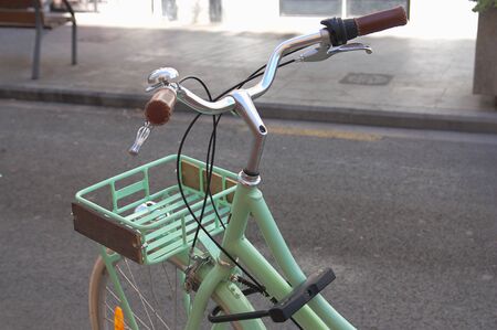 Close-up of a bicycle handlebar parked on the street waiting to be rented by some tourist