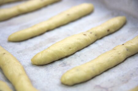 Close-up of a baking tray where there are some handmade elongated donuts when they are still raw...