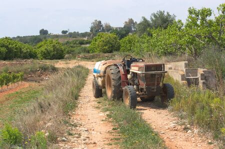 Image of a tractor dedicated to maintaining agricultural fields stands in the middle of a rural roadの写真素材