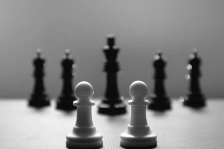 Close-up of some isolated white pawns in front of the black chess pieces. Concept