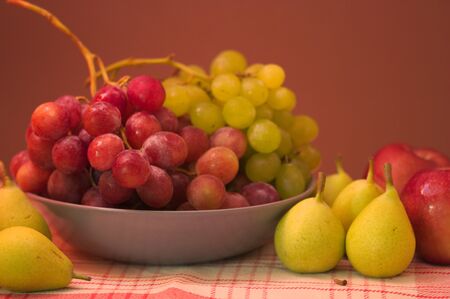 Still life of fruit with white and black grapes, pears, apples, with a brown background with space for texts.の写真素材