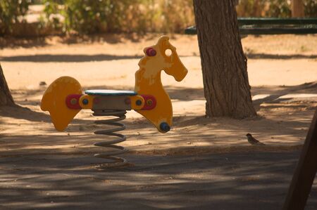 Closeup of a rocking chair in the shape of a horse in a public playground for children in the city