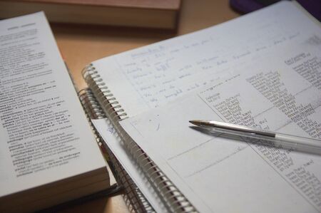 Some notebooks, along with a Spanish English dictionary on the table of an English language student