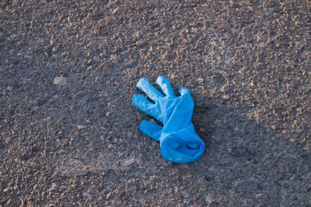 A blue vinyl glove used to protect yourself from the coronavirus on asphalt ground