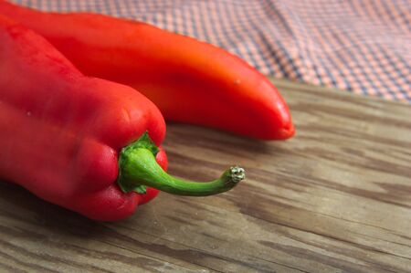 Raw red bell peppers on a wooden cutting board with vegetable space in the background with copy spaceの写真素材