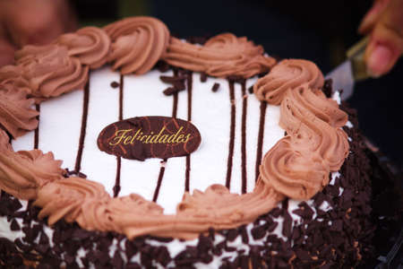Close-up of a chocolate and cream cake with a little sign where it says congratulations in Spanish