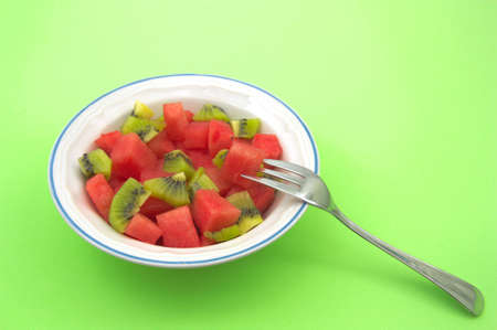 A plate with chopped fruits next to a fork ready to taste the healthy snack. Image with copy space...