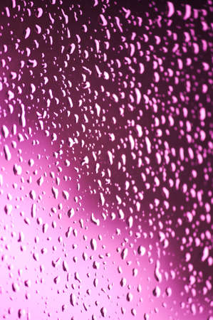 Vertical image of a glass with raindrops with a light gradient of pinkish colorsの写真素材