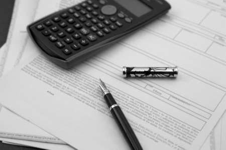 Documents on businesses or banks on which we see a fountain pen and a calculatorの写真素材