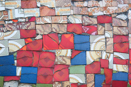 Detail image of a wall decorated with tiles of multiple shapes and colors, following an abstract...