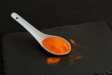 A ceramic spoon with powdered saffron on a slate table with dark background and copy spaceの写真素材