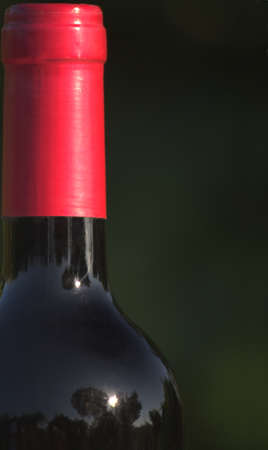 Image of the neck of a bottle of red wine with copy space and green blurred backgroundの写真素材