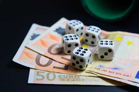 Close-up of a table in which there are five six-sided dice on some 50 euro bills next to a goblet with copy spaceの写真素材