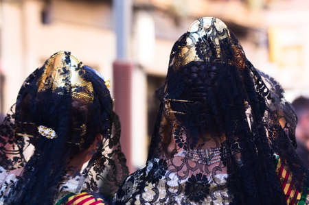 Close-up of two Valencian women dressed as Falleras with the traditional dress and hairstyle with mantilla, combs and jewelsの写真素材