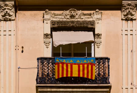 Photograph of a balcony in the center of the Valencian capital from which a flag of the Valencian community hangsの写真素材