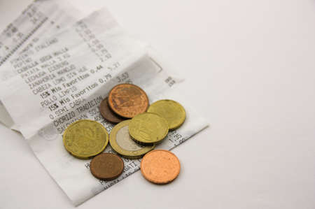 Close-up of some euro cent coins on some shopping tickets that are isolated on white with copy spaceの写真素材