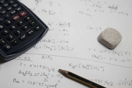 Flat lay of a student table with some chemistry exercises next to a calculator, a pencil and an eraserの写真素材