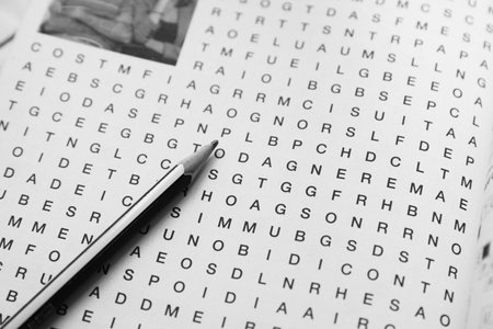 Close-up of an uncompleted word seek or crossword on which there is a two-color pencil. Minimalist black and white background imageの写真素材
