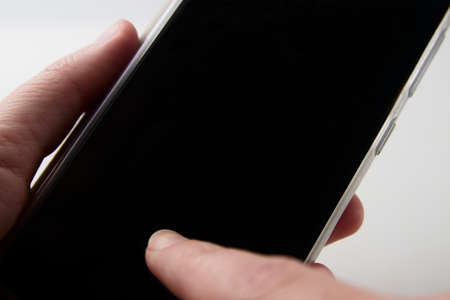 A woman holding and tapping the screen of a smartphone with the screen blacked out