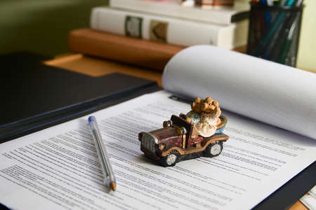 Image of a stroller on a car purchase agreement on a table in an office, with out-of-focus books in the backgroundの写真素材