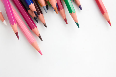 View from above of some messy colored pencils on a white surface with copy spaceの写真素材