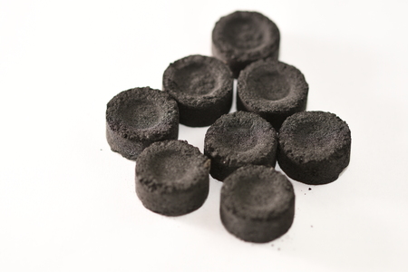 Incense charcoal tablets isolated over whiteの写真素材