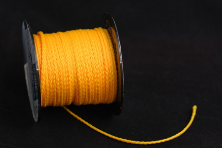 Coil of yellow synthetic rope isolated on black background.の写真素材