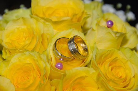 Wedding rings on a bouquet of yellow  rosesの写真素材