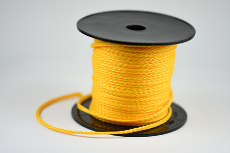 Coil of yellow synthetic rope isolated on white background.