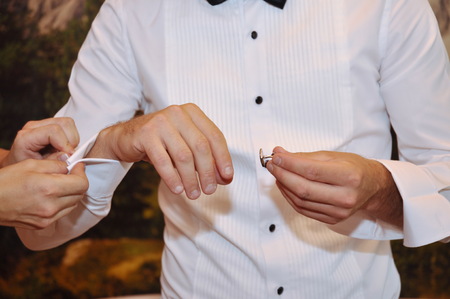 Bride helping her groom with his cufflinks