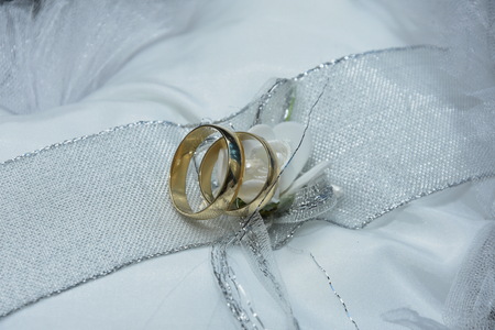 Two Golden Wedding Rings on white satin