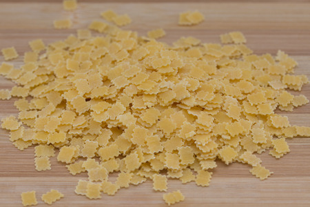 Uncooked small rectangle pasta on wooden plate