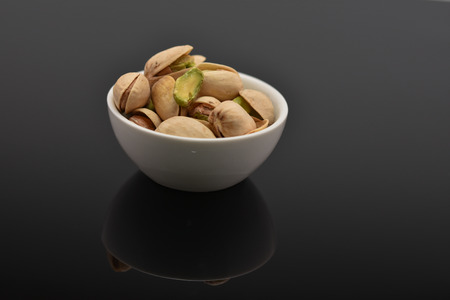 Roasted pistachio seeds with shell in bowlの写真素材