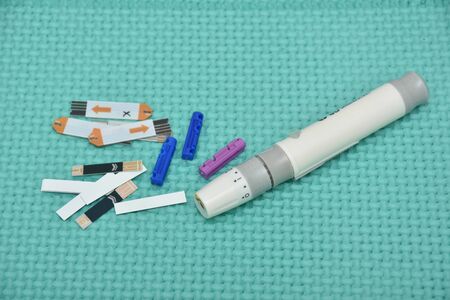 white  Diabetes set with glucometer, lancet, spare needles on green background