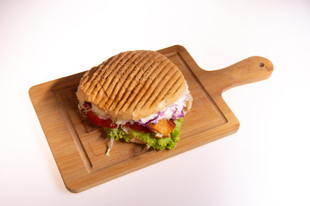 Fresh tasty burger with onions and tomatoes on a wooden plateの写真素材