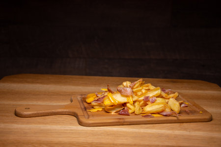 french fries with ham on a wooden plateの写真素材