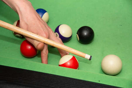 Hand with cue aiming on billiard ball at tableの写真素材