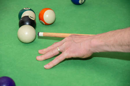 Hand with cue aiming on billiard ball at tableの写真素材