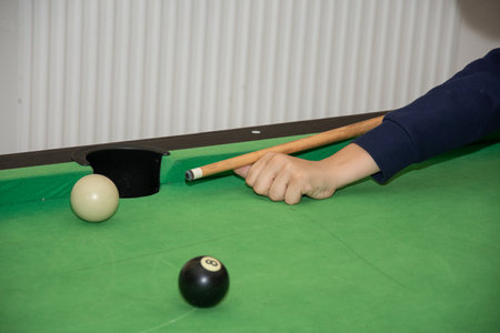Hand with cue aiming on billiard ball at table