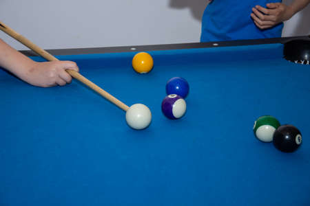 Hand with cue aiming on billiard ball at table