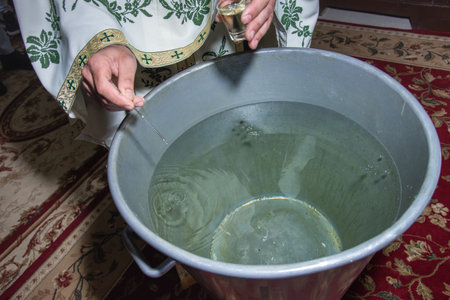 Orthodox priest puts holy oil in baptism vessel In Romania, Cluj