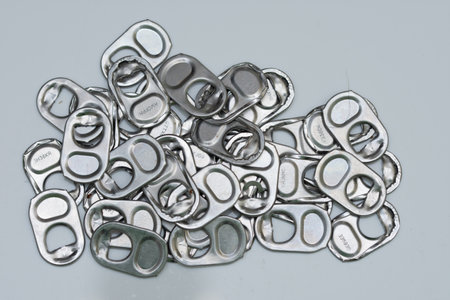 a pile of aluminum can tabs, also known as pull tabs or pop tabs. These tabs are the removable part of the opening mechanism on aluminum beverage cans.の写真素材
