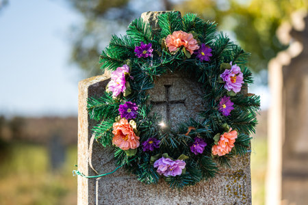 A funeral wreath with artificial flowers placed on a stone gravestone.の写真素材